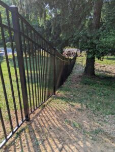 A newly installed black metal fence along a property line under trees by Concord Fence Llc in Wilmington, DE