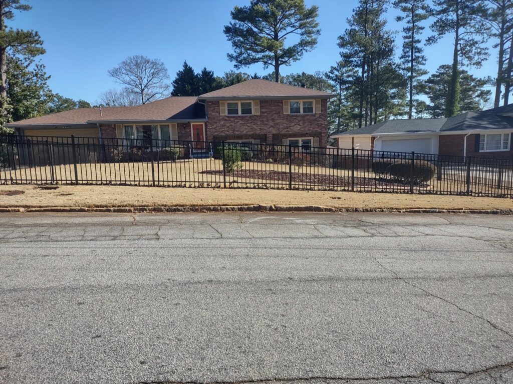 A new black metal fence installed in front of a residential house by Right Now Fencing, LLC in Johns Creek, GA