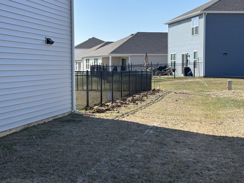 A section of black metal fence installed alongside a residential home by NBBJ Fence LLC in Bluffton, IN.