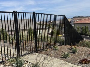 A black metal fence installed on a sloped landscape by Gates Access Solutions in San Diego, CA