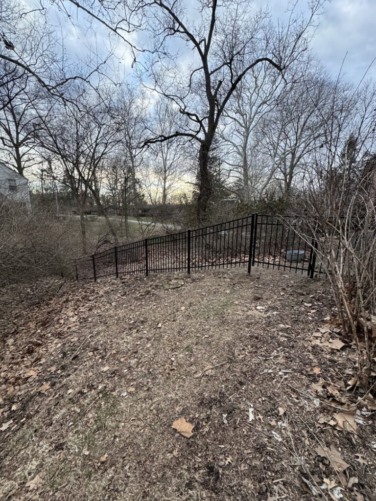 A black metal fence installed on a sloped terrain by Central Ohio Fence in Newark, OH.