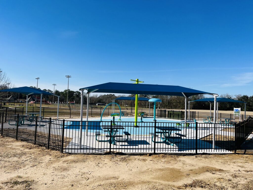 A black metal fence enclosing a splash pad and playground area by Jefcoat Fence Co. Inc. of Hattiesburg, MS