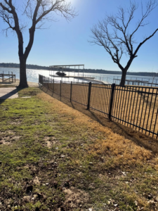 A newly installed black metal fence along a waterfront property by B & S Fence Company in Haltom City, TX