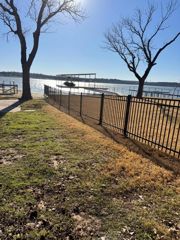 A newly installed black metal fence along a waterfront property by B & S Fence Company in Haltom City, TX