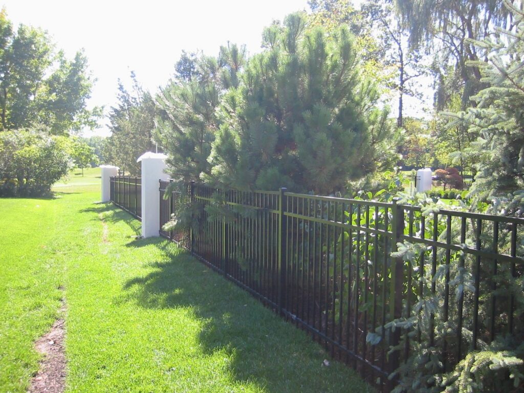 A durable black metal fence with elegant white pillars installed by Freeman Fence in Atlanta, GA.