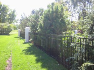 A durable black metal fence with elegant white pillars installed by Freeman Fence in Atlanta, GA.
