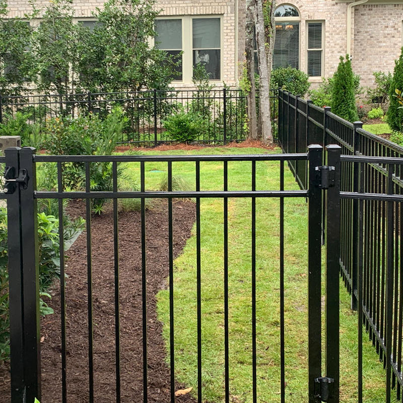 A black metal fence with a gate installed in a landscaped yard by Heavenly Gates Construction LLC in Miami, FL