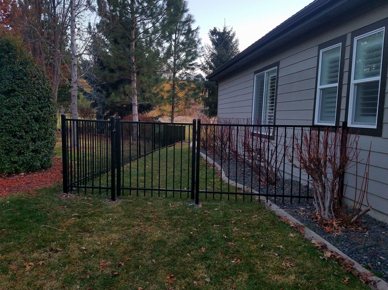 A newly installed black metal fence with a gate along a residential property by Double A Fence LLC in Boise, ID.