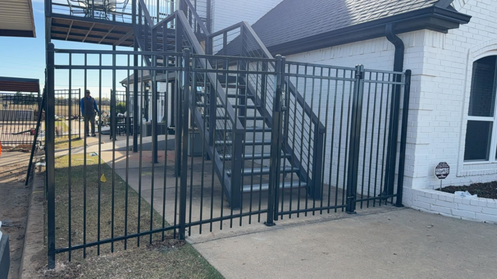 A black metal fence with a gate installed at a residential property by Goliath Fence Systems and Pre-Stain in Oklahoma City, OK.