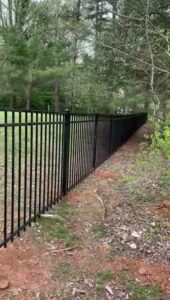 A black metal fence installed in a wooded area by Universal Fence LLC in Drainesville, VA.