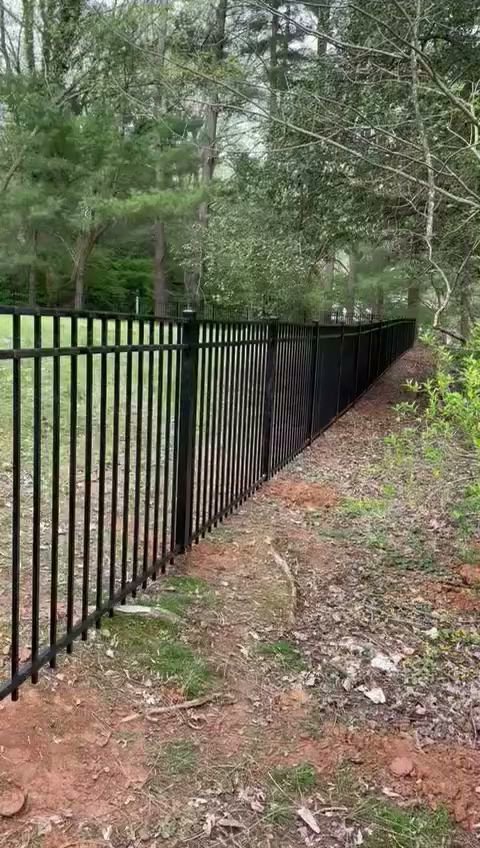 A black metal fence installed in a wooded area by Universal Fence LLC in Drainesville, VA.