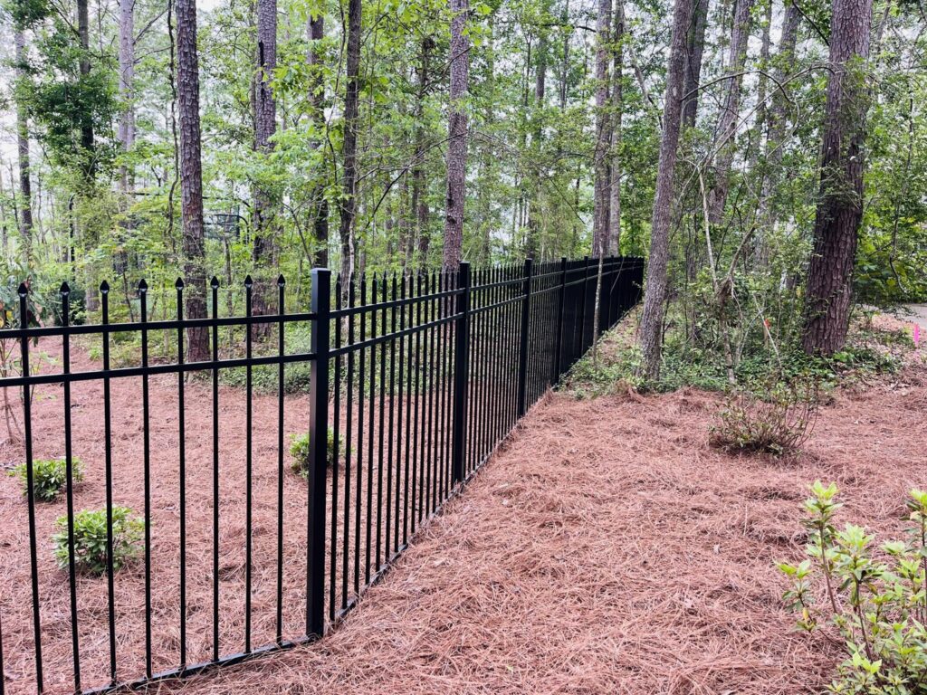 A black metal fence installed along a wooded residential area by Jefcoat Fence Co. Inc. of Hattiesburg, MS