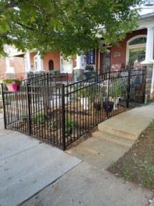 A black metal fence enclosing a small garden area in front of a residential home by DZS Fencing, LLC in Red Lion, PA.