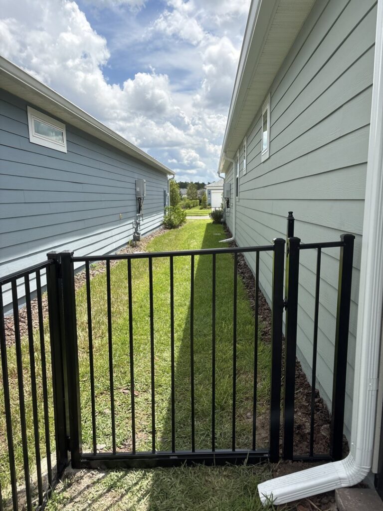 A black metal gate installed between two residential houses by Best Fence and Rail in Jacksonville, FL.