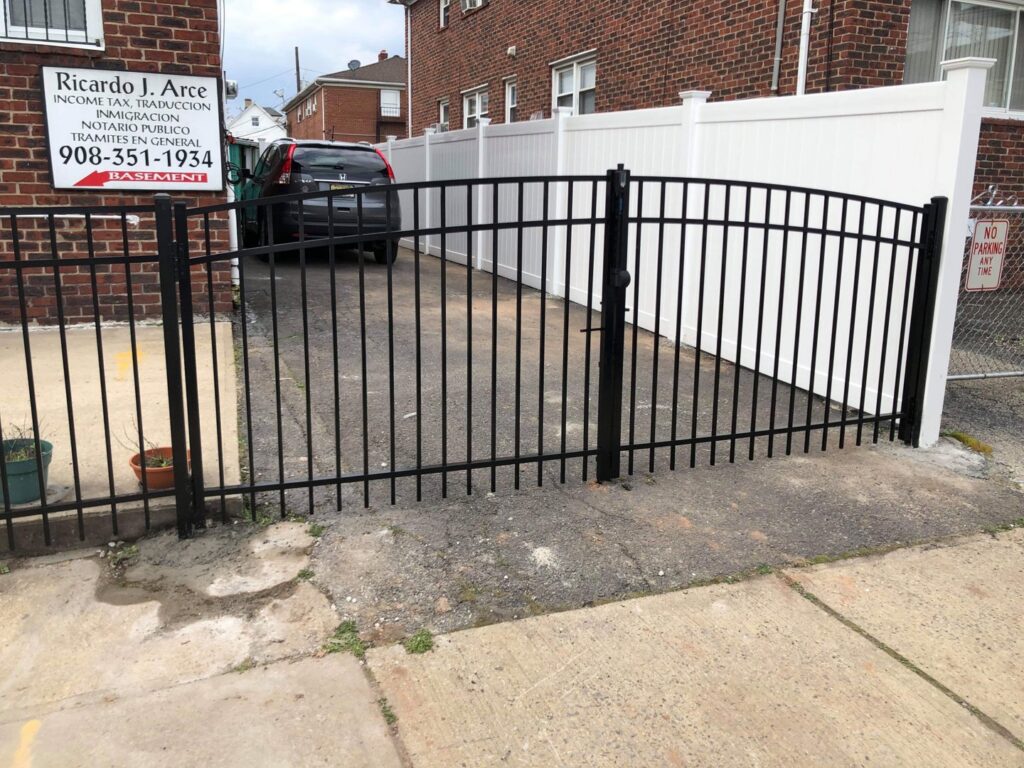 A black metal fence and gate installed adjacent to a white vinyl fence by Brothers Fence in Elizabeth, NJ.