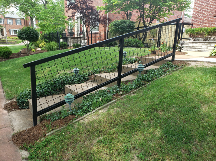 A custom black metal grid railing installed along outdoor concrete steps by Missouri Ornamental Iron and Fence in St Louis, MO.