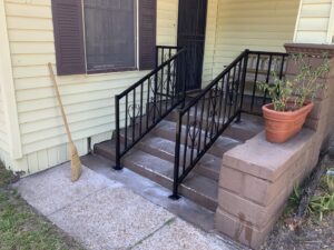 Black metal handrails installed on concrete steps by Ability Burglar Bars in Jacksonville, FL.