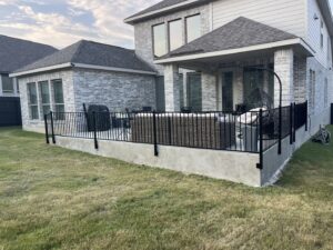 A black metal fence enclosing a patio area next to a house by Liberty Fence & Stain in San Antonio, TX.