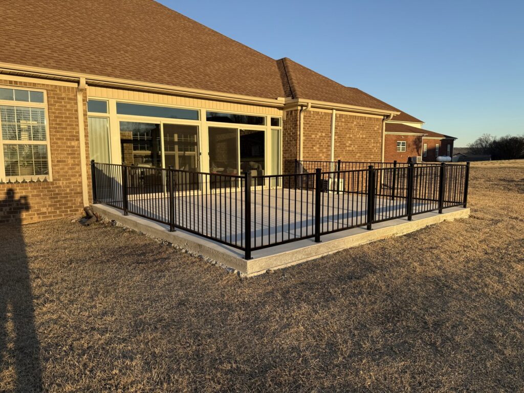 A newly installed black metal railing around a concrete patio by Alabama's Fencing in Huntsville, AL.