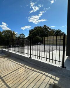 A sturdy black metal perimeter fence installed along a concrete foundation by 865 Fencing in Knoxville, TN.