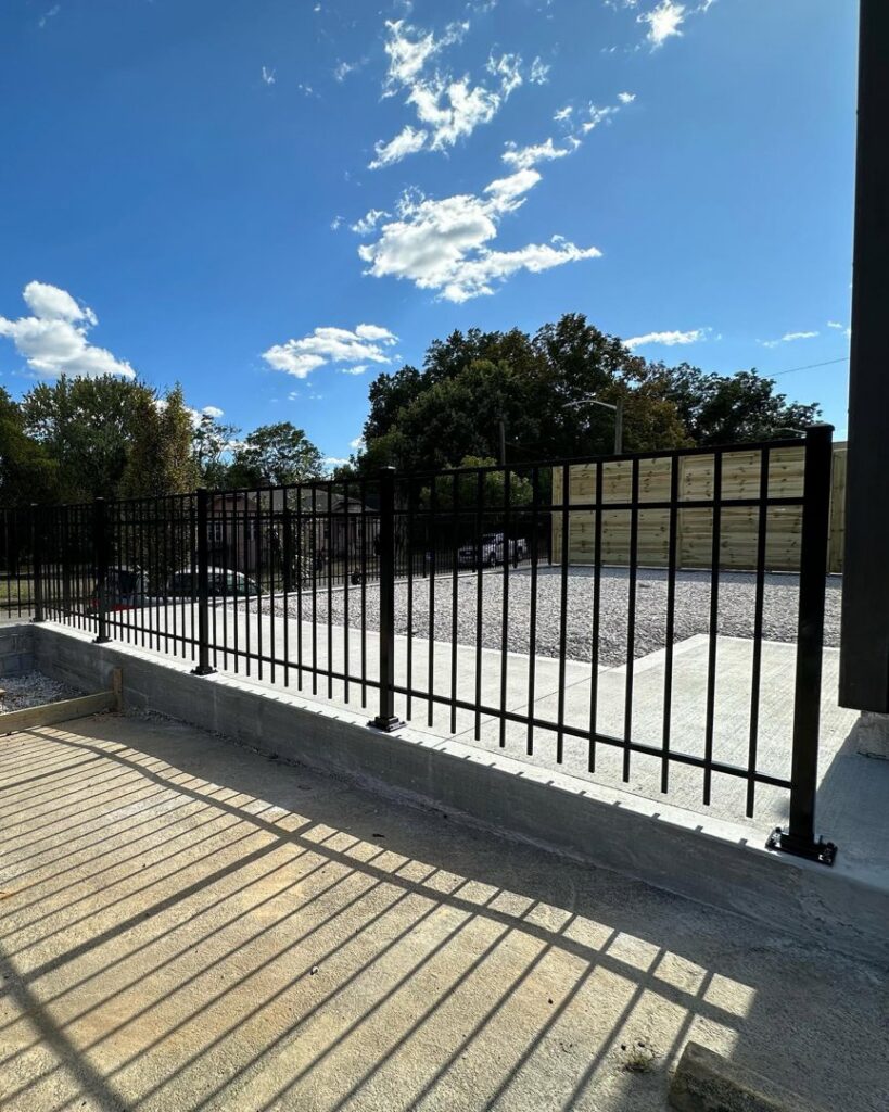 A sturdy black metal perimeter fence installed along a concrete foundation by 865 Fencing in Knoxville, TN.
