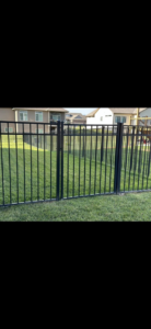 A black metal picket fence installed in a residential yard by NC Fencing LLC in Wichita, KS.