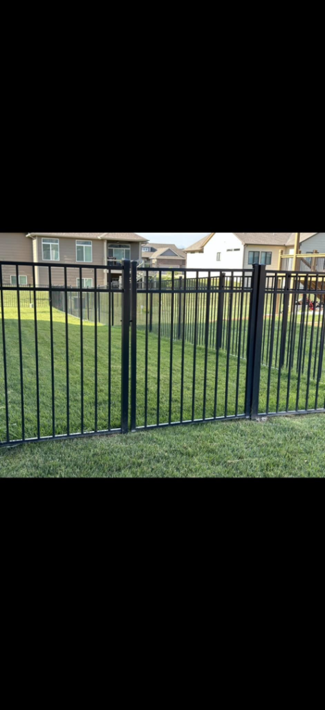 A black metal picket fence installed in a residential yard by NC Fencing LLC in Wichita, KS.