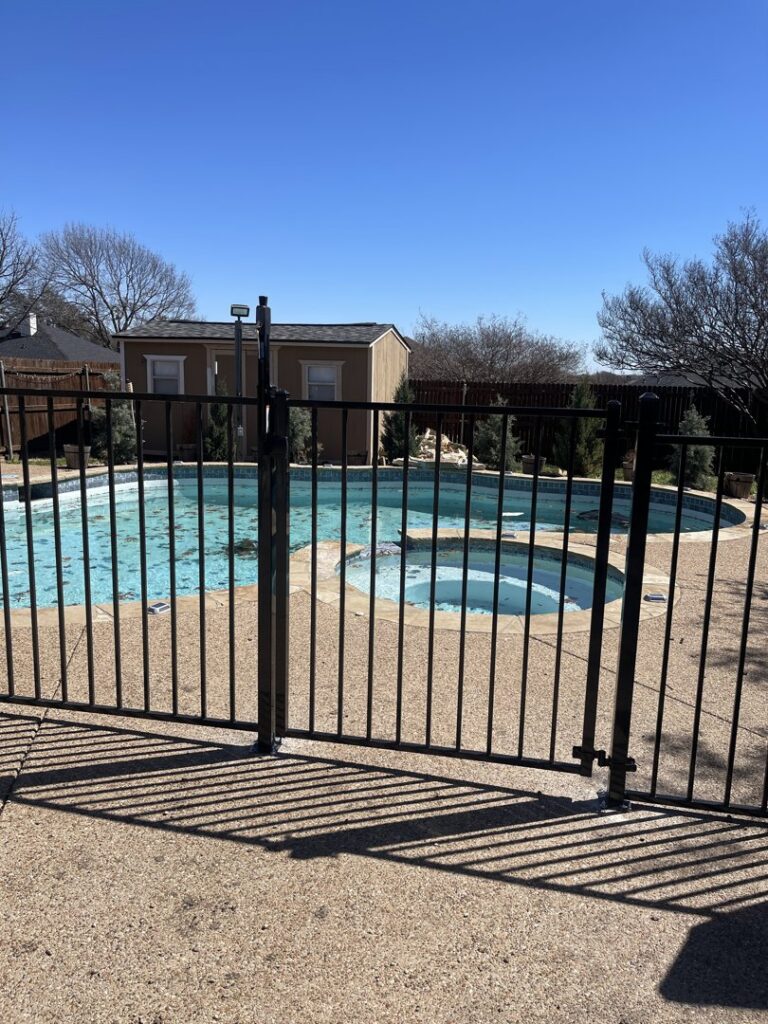A black metal pool fence with a gate installed by Backyard Builders in Rockford, MI.