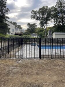 A black metal pool fence with a gate installed by Fence Pros Direct in Saunderstown, RI.