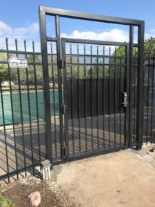 A black metal fence and gate, likely for a pool area, installed by Roy & Son Fencing in Lee's Summit, MO.