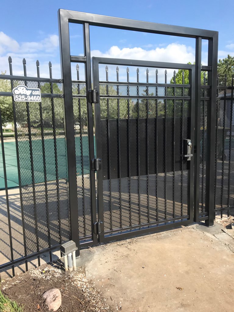 A black metal fence and gate, likely for a pool area, installed by Roy & Son Fencing in Lee's Summit, MO.