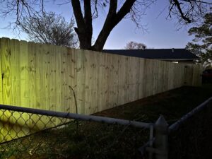 A black metal pool safety fence with a gate, illuminated at night by G L Fence & Remodeling in Arlington, TX.