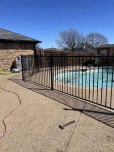 A black metal fence installed around a swimming pool by Backyard Builders in Rockford, MI.