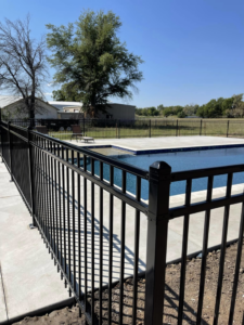 A black metal fence installed around a swimming pool by Fence Restorations LLC in Ponca City, OK.