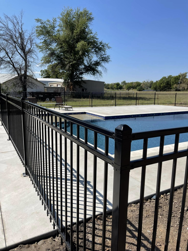 A black metal fence installed around a swimming pool by Fence Restorations LLC in Ponca City, OK.