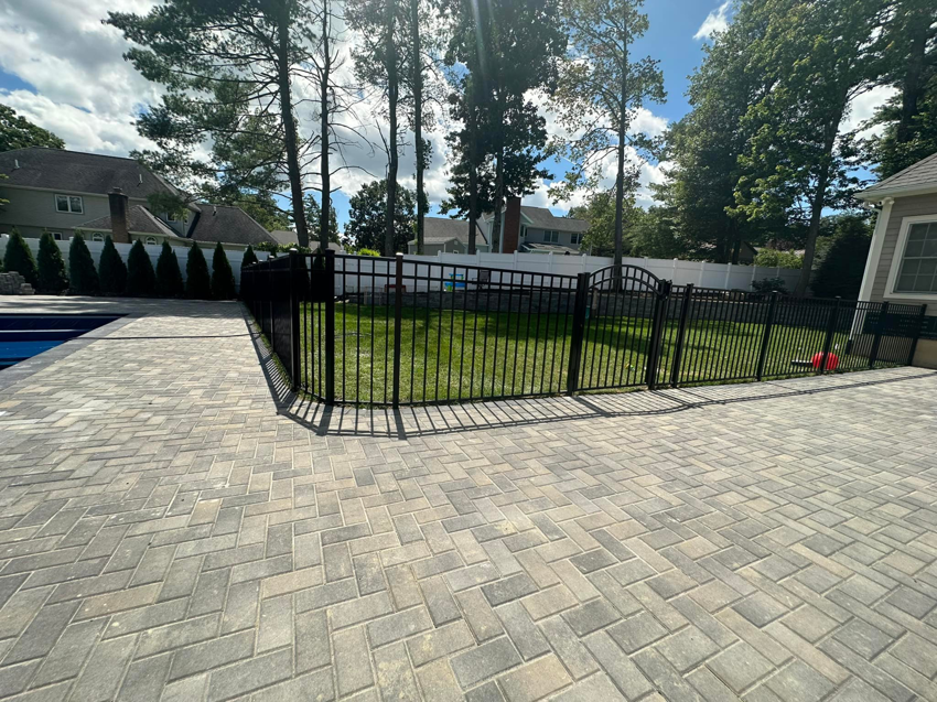 Newly installed black metal fence with a gate around a pool area by Fenced Up, LLC in Ravena, NY.