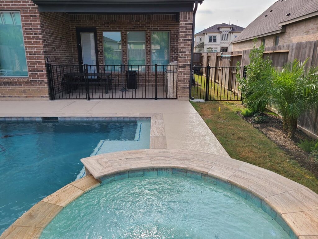 A newly installed black metal pool fence surrounding a swimming pool and patio by GOAT Fence Company in Houston, TX.