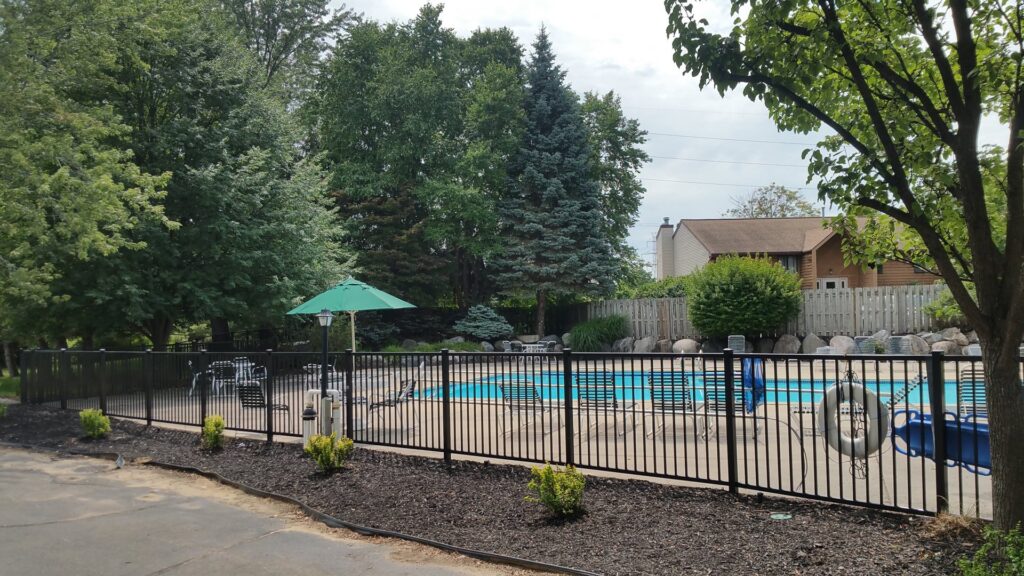 A black metal fence enclosing a swimming pool area, installed by Metrofence in Grand Rapids, MI.