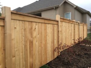 A black metal fence enclosing a swimming pool with a decorative stone wall, installed by Custom Design Fence & Deck, Inc. in Ofallon, MO