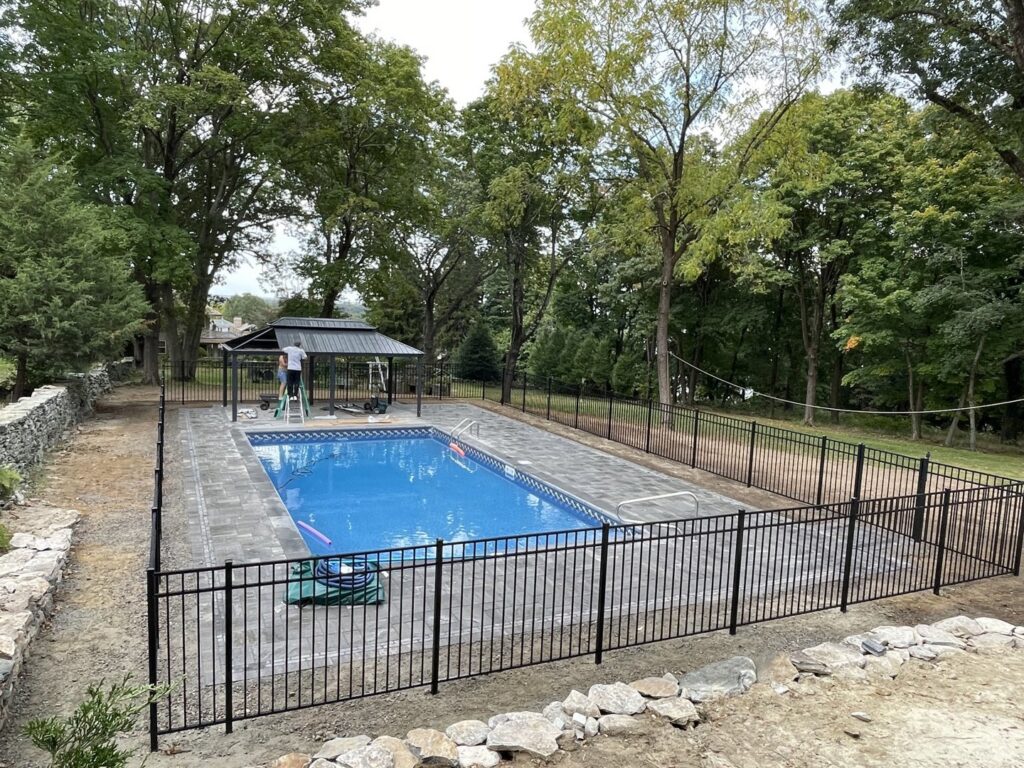 A black metal fence installed around a swimming pool by Fence Pros Direct in Saunderstown, RI.