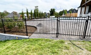 A black metal fence with a gate surrounding a backyard pool area, installed by The Fence Man in Fort Smith, AR