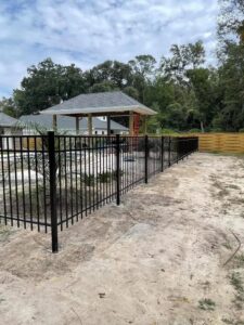 A black metal pool fence with a wood privacy fence in the background by Deep South Services LLC in Biloxi, MS.