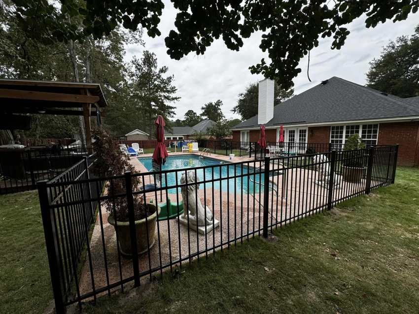 A black metal fence providing safety around a swimming pool, installed by Barwick Fence Company in Savannah, GA.