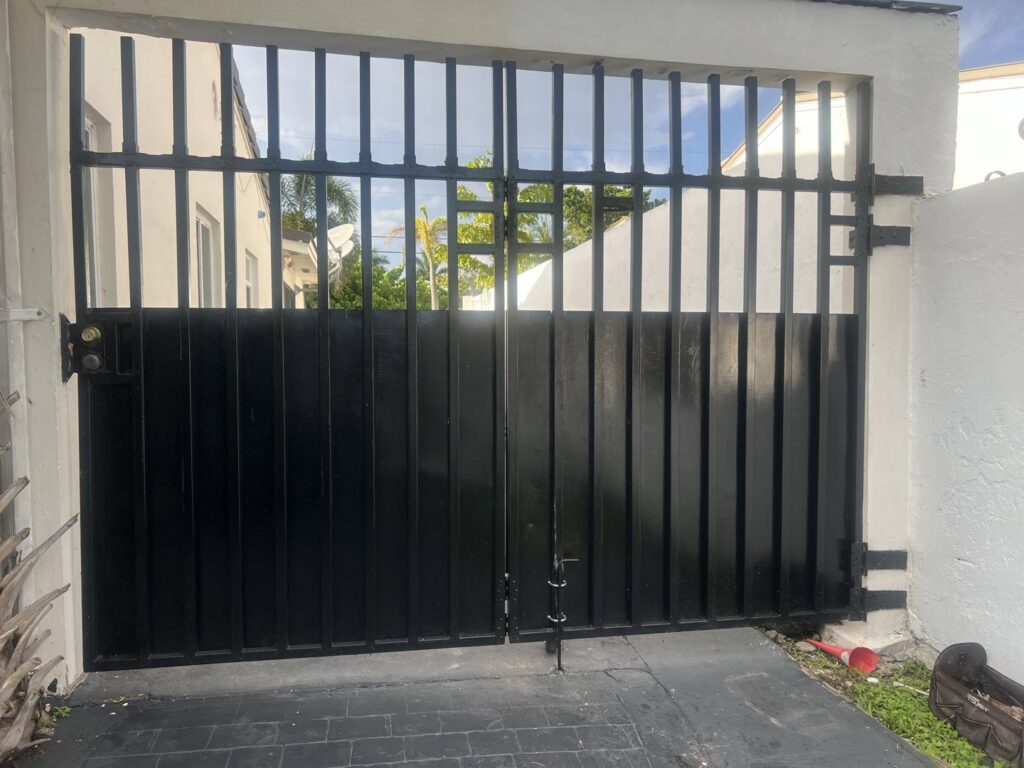 A robust black metal privacy driveway gate installed for security by ARE FENCE LLC in Miami, FL.
