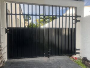 A robust black metal privacy driveway gate installed for security by ARE FENCE LLC in Miami, FL.