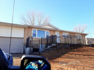 Black metal railing installed along a residential ramp and stairs by James Fencing LLC in Columbia, MO.