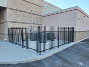 A black metal security fence enclosing HVAC units next to a commercial building, installed by Competitive Fence Contractors LLC in Scottsdale, AZ.