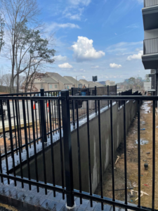 Installation of a black metal security fence along a concrete wall by Castillo Fences in Sacramento, CA.