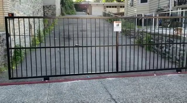 A black metal sliding driveway gate installed by Excel Gates & Services Inc. in New Haven, CT