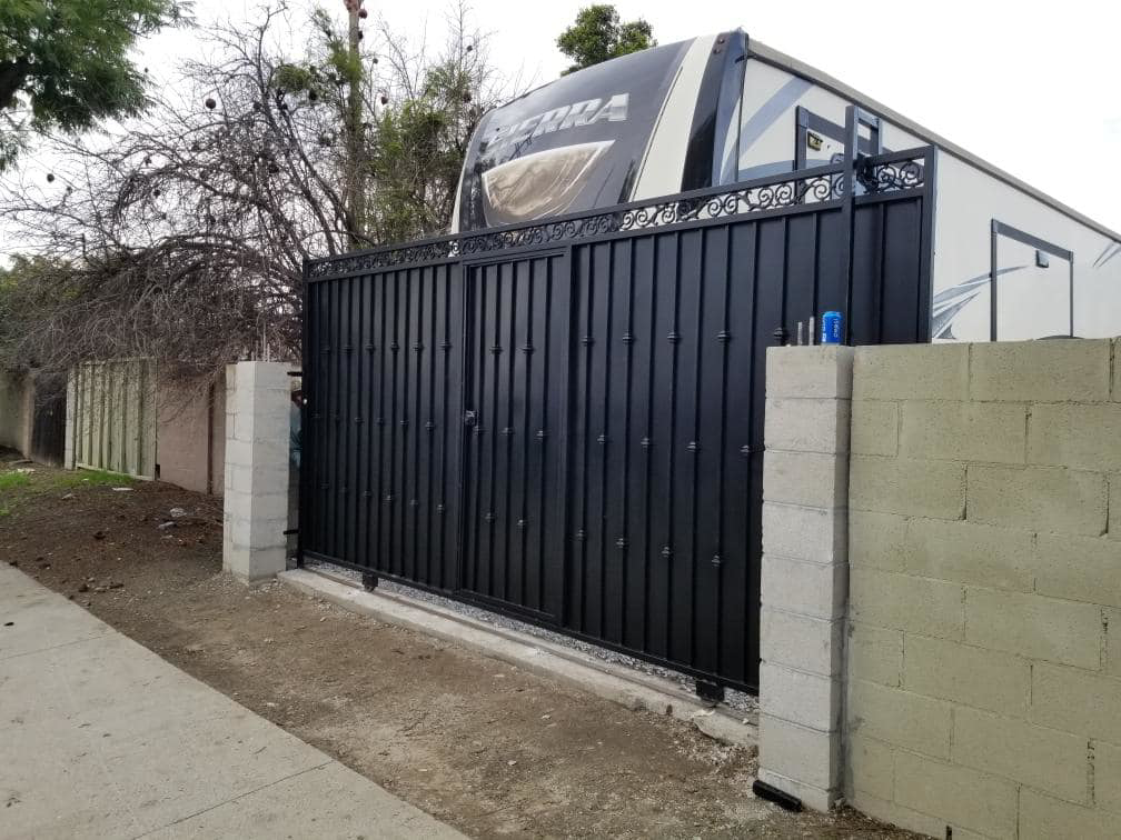 A large black metal sliding gate with decorative elements, installed by Portugal's IronWorks in Los Angeles, CA.
